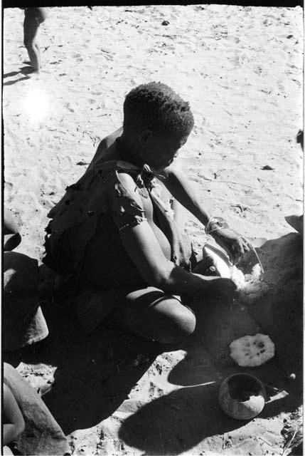 Woman seated scraping a tsama melon