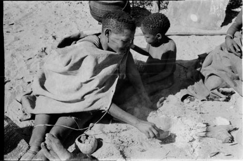 Woman scraping out something that has been cooked in the ashes