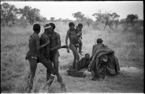 Medicine man held by /Gunda and another person, with "/Qui Navel" holding one of his children and other people present