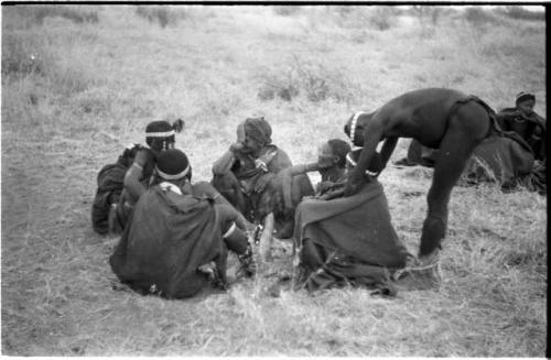 Medicine man curing another person from a group of seated people