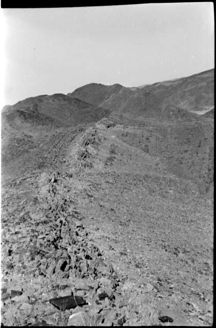 Person walking on side of hill; hill shows tipped strata