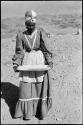 Woman wearing a long dress and turban, standing and mining by panning