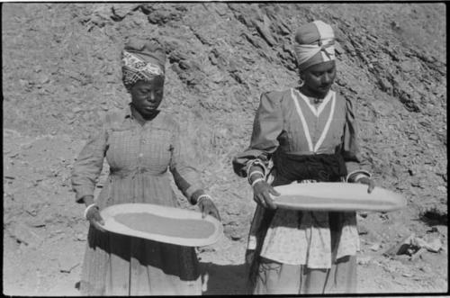 Two women standing and mining by panning