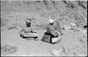 Two women sitting and mining by panning