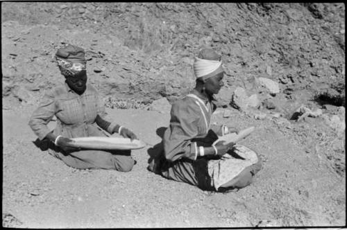 Two women sitting and mining by panning