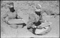 Two women sitting and mining by panning