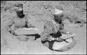 Two women sitting and mining by panning