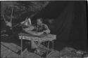 Man working at a table in front of a tent