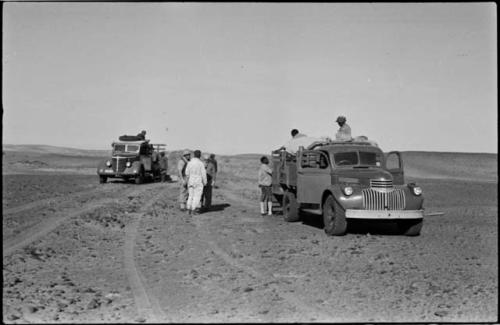 Expedition members standing on and next to trucks