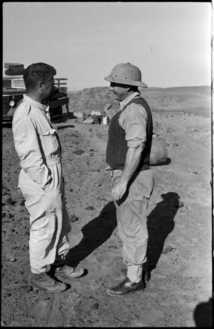 Two expedition members standing, with a truck in the background