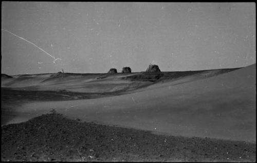 Dune, with three abandoned huts in the distance