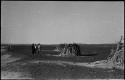 Three men standing near huts