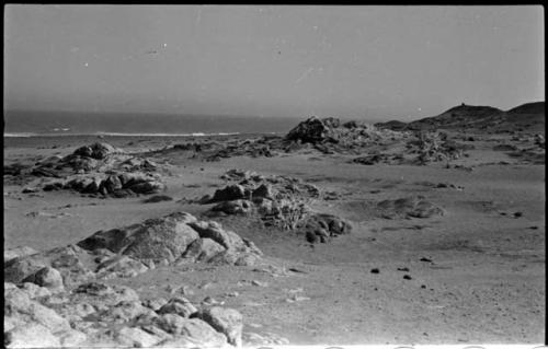 Landscape with sand and rocks, and water in distance