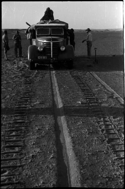 Expedition members standing next to truck and chains laid out ahead of wheels