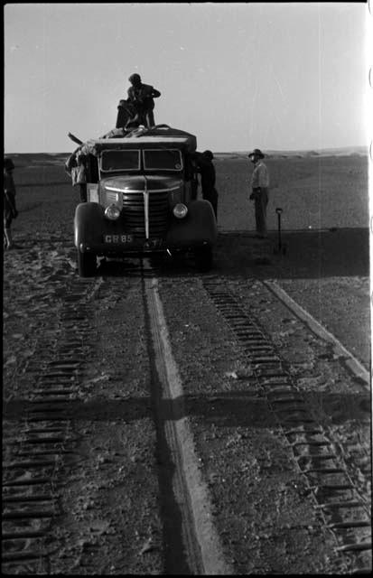 Expedition members standing on and next to truck, and chains laid out ahead of wheels