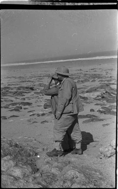 Two expedition members standing on beach looking at water