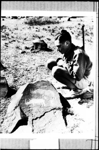 Boy scout looking at a petroglyph of two rhinos at the Rademeyer site