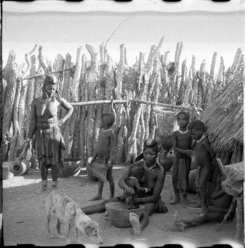 Women and children sitting and standing inside the kraal