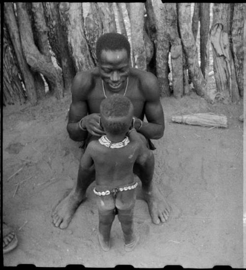 Man sitting with a child standing in front of him