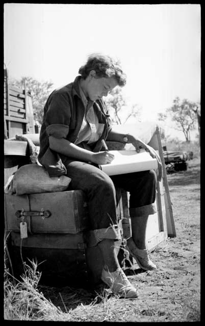 Elizabeth Marshall Thomas sitting on a box and taking notes