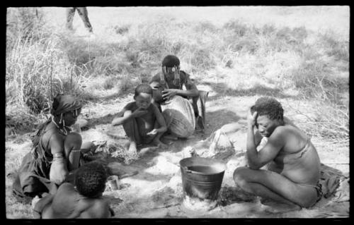 "Old Gau" beside the bucket and unidentified people, all seated