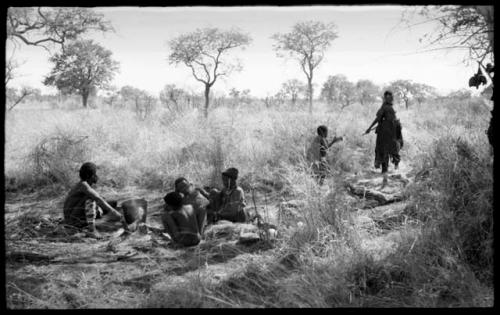 "Old Gau" with a group of unidentified people, all seated, and a bucket