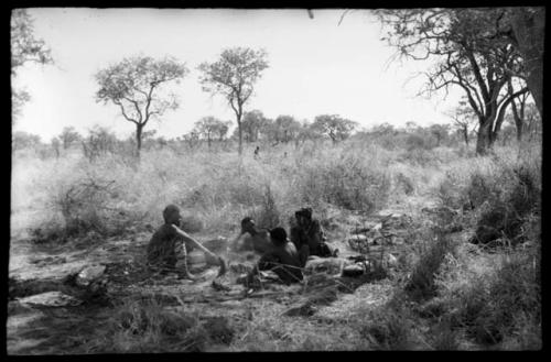 "Old Gau" with a group of unidentified people, all seated, and a bucket