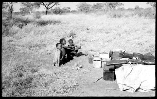 "Little ≠Gao" and ≠Toma's sons, Tsamgao and /Gaishay, beside boxes