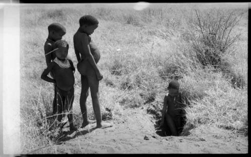 /Gaishay (!U's son), /Gaishay (Di!ai's son), Tsamgao, and "Little ≠Gao" standing in a pit