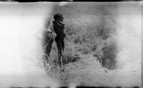 Two Ju/'hoan boys, standing, and one boy, likely "Little ≠Gao", in a pit (damaged negative)