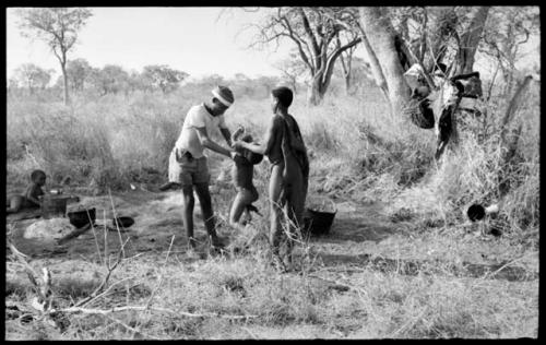 /Gishay ("Old Gau's" son) handing "Little ≠Gao" to //Kushay