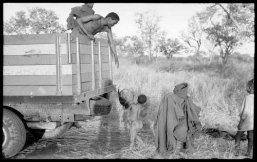 Boy, possibly "Little ≠Gao," handing something to an unidentified Ju/'hoan man in a Dodge truck