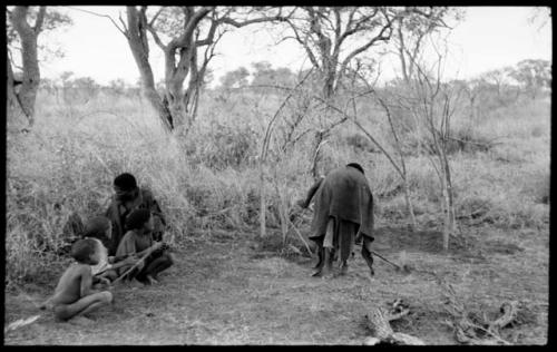 "/Qui Navel" seated with three unidentified boys beside him and //Kushay digging a hole to build a skerm