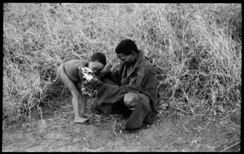 "/Qui Navel" giving "Little ≠Gao" a piece of meat from a bone he is holding