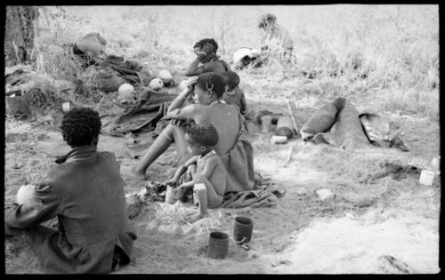 Di!ai, !U, ≠Toma all seated, seen from behind and !Ungka Norna leaning against her mother and Elizabeth Marshall Thomas in the background