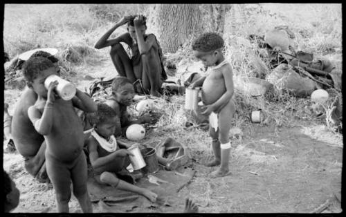 !Ungka Norna, Bau, and /Gaishay (Di!ai's son) holding cans with /Naoka and her son, /Gaishay and other unidentified people