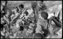 !U, !Unkga Norna playing with a digging stick, ≠Toma, /Gaishay (Toma and ≠U's son) to the left, Tsamgao standing behind !Unkga Norna, their grandmother in the background, and "Gao Lame" wearing a headscarf; part of Elizabeth Marshall Thomas's child study