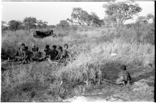 Group of people including !Ungka Norna beside !U, /Gaishay ("Gao Medicine" and Di!ai's son) throwing something to /Gaishay (≠Toma and !U's son), and other identified people, distant view