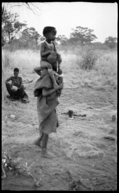 Unidentified, visiting girl, standing with !Ungka Norna on her shoulders