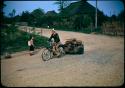 Schoolgirl watching man with bicycle-drawn cart