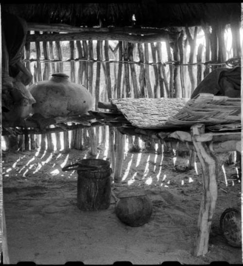 Woven mat, wooden bucket with leather handle, and large pot inside a storage hut