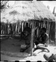 Women sitting and eating in the shade of a thatched roof