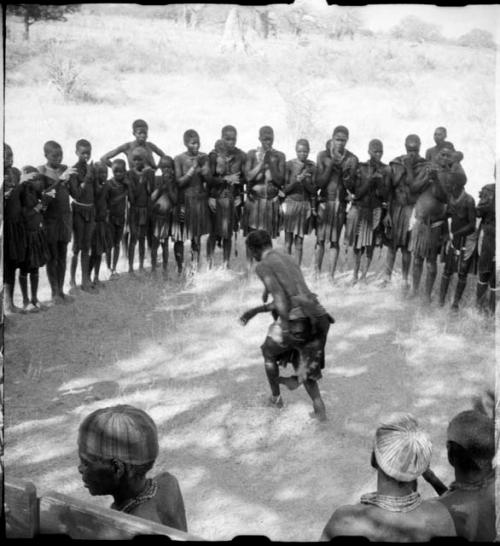 Woman dancing in the center of a circle of women clapping and singing