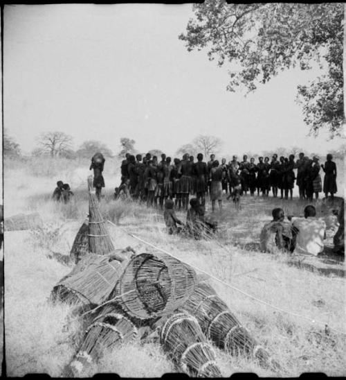 Circle of women dancing, clapping and singing, with fish traps in foreground