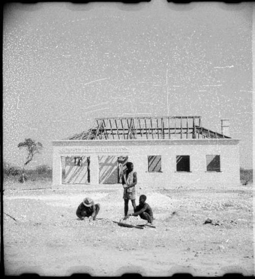 Men sitting and standing in front of a clinic under construction