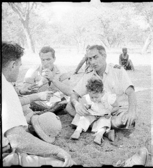 Senhor Simões sitting with his baby on his lap, and Heiner Kretschmar sitting beside him