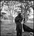 Kernel Ledimo wearing clothing and head covering to protect against tsetse flies, and untangling tent ropes