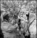 Laurence Marshall taking a light reading of Lorna Marshall, and both are wearing clothing and head coverings to protect against tsetse flies