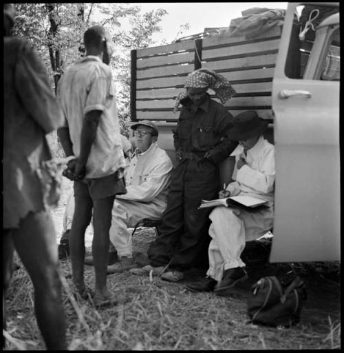 Man talking with Kernel Ledimo, Nicholas England and Lorna Marshall next to expedition truck