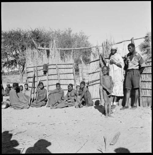 Group of adults and children standing and sitting by their fence